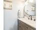 Bathroom featuring modern vanity with white countertop, black faucet, round mirror, and decorative artwork at 1470 S Quebec Way # 8, Denver, CO 80231