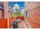 Private brick-enclosed backyard area with a dining set, grill, and access to a green space beyond the fence at 3070 Colorado Blvd, Denver, CO 80207