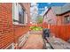 Enclosed brick backyard featuring an outdoor dining set, grill, patio stones and view of green grass at 3070 Colorado Blvd, Denver, CO 80207