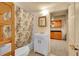 Renovated basement bathroom with a sink vanity, tub, shower, and view into kitchen at 3070 Colorado Blvd, Denver, CO 80207