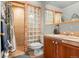 Unique bathroom featuring a glass block partition for the shower, complemented by a vintage vanity and colorful mosaic floor tiles at 7400 W Quincy Ave, Littleton, CO 80123