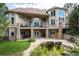 Two-story home with multiple balconies, stone pillars, lush landscaping, and serene pond at 5170 Pinyon Jay Rd, Parker, CO 80134