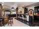 Basement wet bar with dark cabinets, stone accents, granite counters, and seating at 5170 Pinyon Jay Rd, Parker, CO 80134
