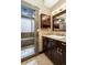 Bathroom with tiled shower, glass block window, granite counter, and dark wood cabinets at 5170 Pinyon Jay Rd, Parker, CO 80134