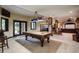 Large game room with pool table, stone pillars, wet bar, fireplace, and backyard access at 5170 Pinyon Jay Rd, Parker, CO 80134