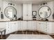 Elegant main bathroom featuring dual sinks, round mirrors, and white cabinetry at 5170 Pinyon Jay Rd, Parker, CO 80134