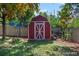 Well-kept backyard featuring a red storage shed with a white door and a lush green lawn at 4585 S Elati St, Englewood, CO 80110