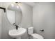 Powder room featuring a pedestal sink, a round mirror, and a modern light fixture at 2078 S Holly St # 2, Denver, CO 80222