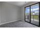 A simple bedroom with gray carpet and a sliding glass door to a balcony at 2078 S Holly St # 2, Denver, CO 80222