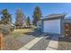 Detached garage with a modern door and gravel driveway, surrounded by lush greenery at 7100 E 5Th Ave, Denver, CO 80220