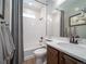 Well-lit bathroom featuring a tub with shower, white subway tile and vanity with a dark wood cabinet at 21927 E 51St Dr, Aurora, CO 80019