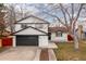 Charming two-story home featuring a black garage door and painted white brick at 6426 Zang Ct, Arvada, CO 80004