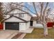 Charming two-story home featuring a black garage door and painted white brick at 6426 Zang Ct, Arvada, CO 80004