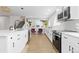 Open kitchen with white cabinets, stainless appliances, new flooring, and modern fixtures at 6426 Zang Ct, Arvada, CO 80004