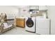 Bright laundry room with tile floors, wooden cabinets, sink, and modern washer and dryer at 4253 Hooker St, Denver, CO 80211