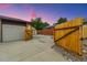 Backyard view of the two-car garage, privacy fence, and wooden gate leading to the driveway at 5954 W Leawood Dr, Littleton, CO 80123
