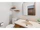Cozy half bathroom featuring a sink with a traditional faucet, a toilet, and floating shelves at 5954 W Leawood Dr, Littleton, CO 80123