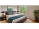 Comfortable bedroom features a queen-sized bed, and hardwood floors, and a view of the mature landscape at 5954 W Leawood Dr, Littleton, CO 80123