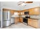 Bright kitchen with stainless steel appliances, wood cabinets, and a tiled backsplash at 5954 W Leawood Dr, Littleton, CO 80123