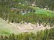 Aerial view shows multiple buildings and an enclosed horse training pen, surrounded by a dense green forest at 11652 Camp Eden Rd, Golden, CO 80403