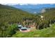 Aerial view showcases the secluded home with green pastures and a forest with mountain views at 11652 Camp Eden Rd, Golden, CO 80403