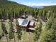 Aerial view of a log-sided home with a deck and solar panels, surrounded by a lush forest landscape at 11652 Camp Eden Rd, Golden, CO 80403