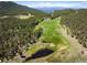 Aerial view of land with ponds, yellow wildflowers, and dense pine and aspen trees; snow-capped mountains in the distance at 11652 Camp Eden Rd, Golden, CO 80403