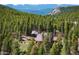 Aerial view of mountain acreage featuring home, trees and snow-capped mountains in the distance at 11652 Camp Eden Rd, Golden, CO 80403