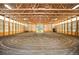 Large indoor riding arena with sand floor, wood framing, and lighting fixtures at 11652 Camp Eden Rd, Golden, CO 80403