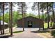 Exterior view of a barn featuring brown siding, green trim, and tall pine trees in a landscaped yard at 11652 Camp Eden Rd, Golden, CO 80403