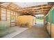 Barn interior with hay storage, wash area, and stalls; open garage door at 11652 Camp Eden Rd, Golden, CO 80403