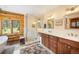 This primary bathroom features a double sink vanity, a tiled shower with glass doors, and a large window to the forest beyond at 11652 Camp Eden Rd, Golden, CO 80403