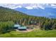 Picturesque landscape featuring wooden outbuildings, a green meadow, and snow-capped mountains in the background at 11652 Camp Eden Rd, Golden, CO 80403