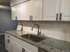 Close up of the kitchen showing granite countertops, stainless steel sink, and white cabinets at 7375 E Quincy Ave # 106, Denver, CO 80237