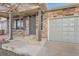 Inviting front porch with stone accents, gray door, gray columns and an attached two car garage at 5506 Malta St, Denver, CO 80249