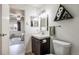 Well-lit bathroom with a mirror, a dark vanity, and a view to the bedroom at 17493 E Mansfield Ave # 1231L, Aurora, CO 80013