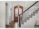 Bright foyer featuring a wood door, a modern chandelier, and stairs with an ornate black and white banister at 3074 Castle Butte Dr, Castle Rock, CO 80109