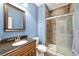 Bathroom featuring walk-in shower with glass doors, single vanity and blue accent wall at 6987 Esperanza Dr, Castle Pines, CO 80108