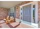 Charming front porch featuring a brick facade, wooden chairs, and a gray front door with sidelights at 6987 Esperanza Dr, Castle Pines, CO 80108