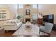 Bright living room with a fireplace, tall windows, and views of the manicured yard at 6987 Esperanza Dr, Castle Pines, CO 80108