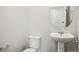 Elegant half bathroom featuring a pedestal sink, toilet and an oval mirror at 2222 Flower Blossom Ave, Brighton, CO 80601