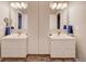 Bathroom featuring double sinks with a large mirrors, modern fixtures, and a shared central storage space at 15818 W 95Th Ave, Arvada, CO 80007