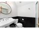 Charming bathroom featuring black wainscotting, round mirror, and a shower with glass door at 7225 Box Canyon Rd, Sedalia, CO 80135