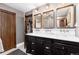Elegant bathroom featuring a dual sink vanity with marble countertop, decorative mirrors, and wood door at 7225 Box Canyon Rd, Sedalia, CO 80135