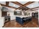 Spacious kitchen features an island with seating, custom cabinets, stainless steel appliances, and wood beam ceiling at 7225 Box Canyon Rd, Sedalia, CO 80135