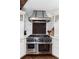 Modern kitchen with stainless steel range and hood, white marble backsplash, and custom cabinets at 7225 Box Canyon Rd, Sedalia, CO 80135