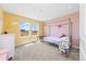 Cozy bedroom with rainbow decoration and bright yellow walls with a window overlooking the landscape at 24222 E Canyon Pl, Aurora, CO 80016