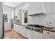 White kitchen featuring modern appliances, subway tile backsplash, hardwood floors, and natural light from windows at 685 N Emerson St, Denver, CO 80218
