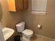 Bathroom features a toilet, sink, and window with blinds and cabinets at 21300 E 42Nd Ave, Denver, CO 80249