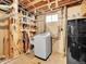Unfinished basement with laundry area, storage shelves, and a compact refrigerator at 5225 Beech St, Arvada, CO 80002